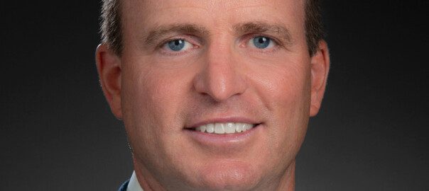 Professional headshot of smiling man in blue suit