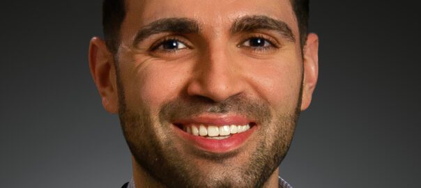 A man with a beard and suit jacket smiling.