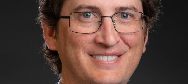 A man with glasses and a suit jacket