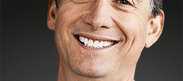 Smiling man in a suit jacket.