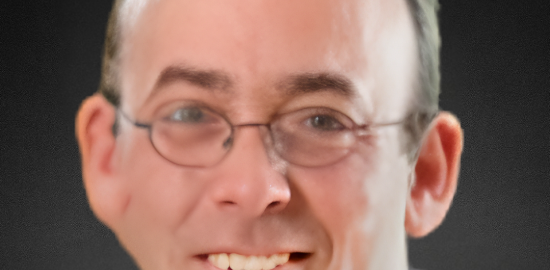 Smiling man with glasses against dark background.
